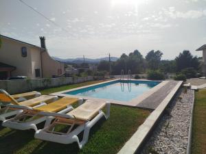a swimming pool with lounge chairs next to a house at Villa Beco - Moradia de Luxo com até 6 Quartos e Piscina Privada in Monção