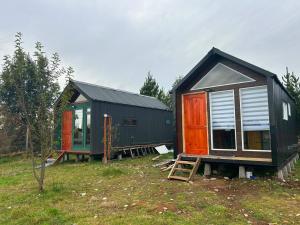 two small houses sitting on a grass field at Dyl Tiny House con Jacuzzi in Puerto Montt