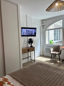 a bedroom with a flat screen tv and a chair at Charmant studio avec terrasse in Fécamp