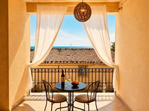 a balcony with a table and chairs and a window at Calauriia Apartments Marzamemi in Marzamemi