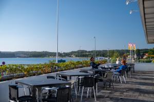 Menschen sitzen an Tischen auf einer Terrasse in der Nähe des Wassers in der Unterkunft Hotel Østersø in Aabenraa