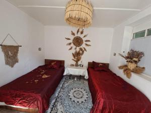 a bedroom with two beds and a table and a chandelier at BOHO House in Cholpon-Ata +9 photos