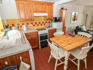 a kitchen with a wooden table and white chairs at Swallow Cottage in Cowbridge +16 photos