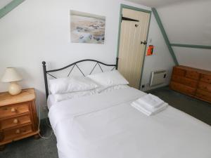a bedroom with a white bed and a wooden night stand at Swallow Cottage in Cowbridge