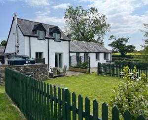 a white house with a fence and a yard at Swallow Cottage in Cowbridge