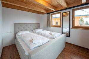 a bedroom with a large bed with white sheets at Almhäuser Filzsteinalpe Almhaus 204 in Krimml