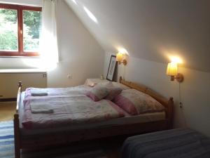a bedroom with a bed with two lamps and a window at Winterberg Vendégház in Óbánya