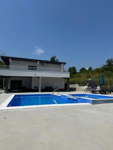 a swimming pool in front of a house at Villa Imperium Indoor & Outdoor Pool Riverfront Bjelašnica View in SJJ