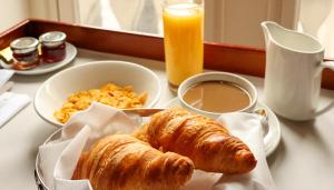 a table with a plate of croissants and eggs and orange juice at Hotel de la Gare de Troyes in Troyes
