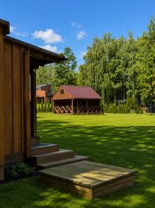 a house with a porch and a field with a barn at Marių įlanka camping in Marijampolė