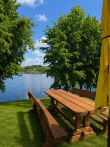 a picnic table and an umbrella next to a lake at Marių įlanka camping in Marijampolė +2 photos