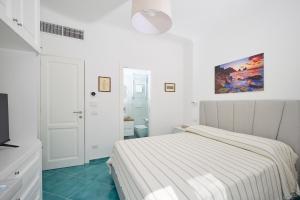 a white bedroom with a bed and a bathroom at La Marilena Penthouse in Capri