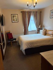 a bedroom with a bed and a chair and a window at Atlantic Guest House in Donegal