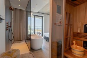 a bathroom with a bath tub and a bedroom at Suite O in Ostend
