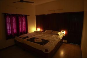 a bedroom with a large bed with two lamps on it at Hidden Heaven Villa in Puducherry Airpoert +4 photos