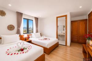 a hotel room with two beds with roses on them at Merry Land Hotel Da Nang in Danang