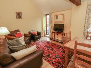 a living room with a leather couch and a television at The Hayloft in Wigton