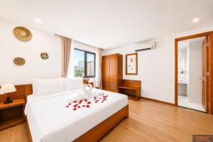 a bedroom with a white bed with red roses on it at Merry Land Hotel Da Nang in Danang