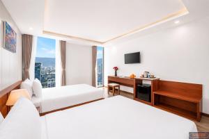 a hotel room with two beds and a desk at Merry Land Hotel Da Nang in Danang