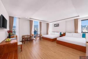 a hotel room with two beds and a table at Merry Land Hotel Da Nang in Danang