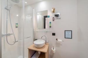 a white bathroom with a sink and a shower at Logis Hotel de l'Artuby in Séranon