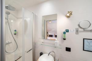a white bathroom with a shower and a mirror at Logis Hotel de l'Artuby in Séranon