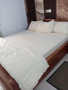 ein Bett mit weißen Laken und Kissen in einem Zimmer in der Unterkunft Hotel Mandelson in Godomey