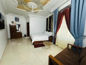 ein Schlafzimmer mit einem Bett und einer Couch in einem Zimmer in der Unterkunft Hotel Mandelson in Godomey