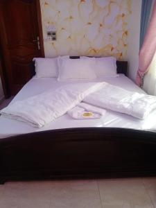 ein Bett mit weißen Laken und einem Teller darauf in der Unterkunft Hotel Mandelson in Godomey