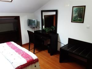 a bedroom with a bed and a desk and a television at Residência Machado in Horta