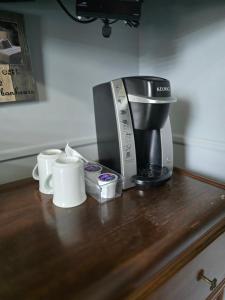 a coffee maker and cups on a wooden counter at Pavillon Beauséjour in Amqui