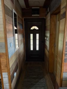 a hallway with a black door and wooden walls at Kod Svastike in Džepare +3 photos