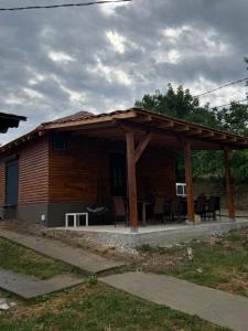 a wooden pavilion with tables and chairs in front of a building at Kod Svastike in Džepare