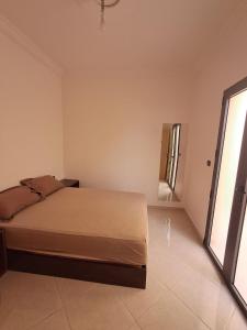 a bedroom with a bed and a large window at Résidence Maya 1 près de la plage in Ras El Ma +3 photos