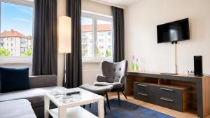 a living room with a couch and a desk with a tv at Hotel Leitner in Kaufbeuren