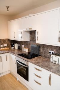 a kitchen with white cabinets and a stove top oven at The Galleries No 3 in Spean Bridge