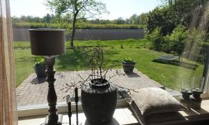 a window with a vase and a lamp on a table at Vechtdalchalet, De Wilg in Rheezerveen