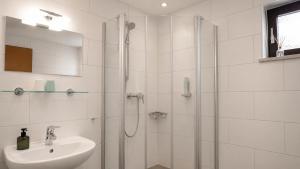 a white bathroom with a shower and a sink at Hotel Leitner in Kaufbeuren +41 photos