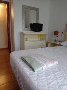 a bedroom with a white bed and a mirror at villaislandia in Oropesa del Mar