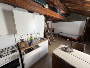 a kitchen with white cabinets and a stove top oven at Maison Jaune 26 in Aosta