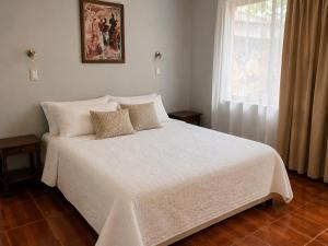 a bedroom with a white bed with pillows and a window at NEW Hotel Casa del Profesor in Iquique