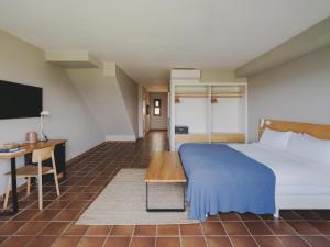 a bedroom with a bed and a desk and a tv at Hotel Es Blau Des Nord in Colonia de Sant Pere +86 photos