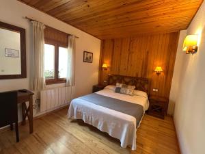 ein Schlafzimmer mit einem Bett und einer Holzdecke in der Unterkunft Hotel Els Puis in Esterri d'Àneu