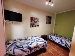a bedroom with two beds and a flat screen tv at NEW Hotel Casa del Profesor in Iquique