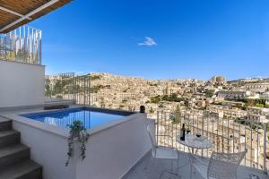 ein Balkon mit Pool und einem Tisch mit Stühlen in der Unterkunft Itria Modica in Modica