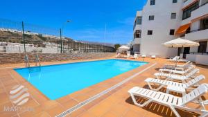 a swimming pool with lounge chairs next to a building at Propiedad San Salvador in Mogán