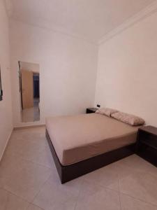 a bed in a room with a white wall at Résidence Maya 1 près de la plage in Ras El Ma