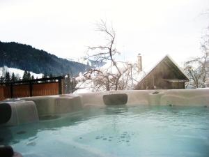 a hot tub covered in snow in front of a house at Riders Refuge - Chalet Eterle in Morzine