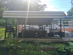 a white pavilion in a yard with plants at Camper with Queen and bunk bed in Robbinsville