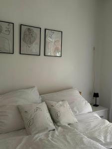 a white bed with four pictures on the wall at Fehér Villa in Kővágóörs
